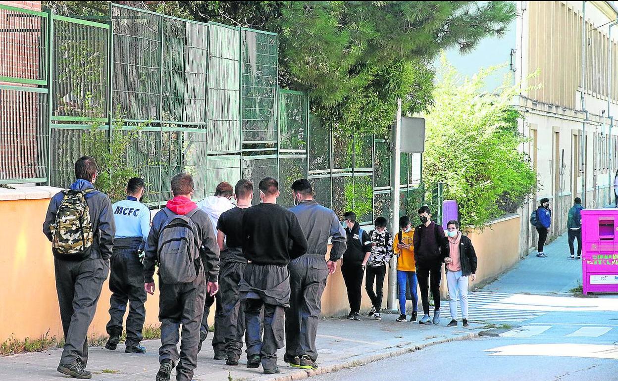 Arriba, jóvenes en los alrededores de un instituto de la ciudad. A la derecha, policías locales durante una patrulla. 