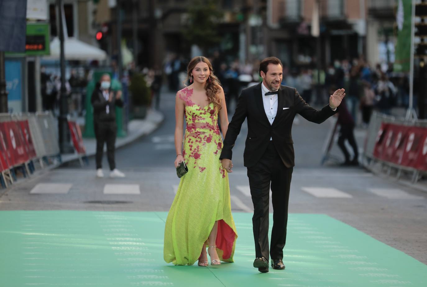 Padre e hija saludan a los asistentes a su paso por la alfombra verde.