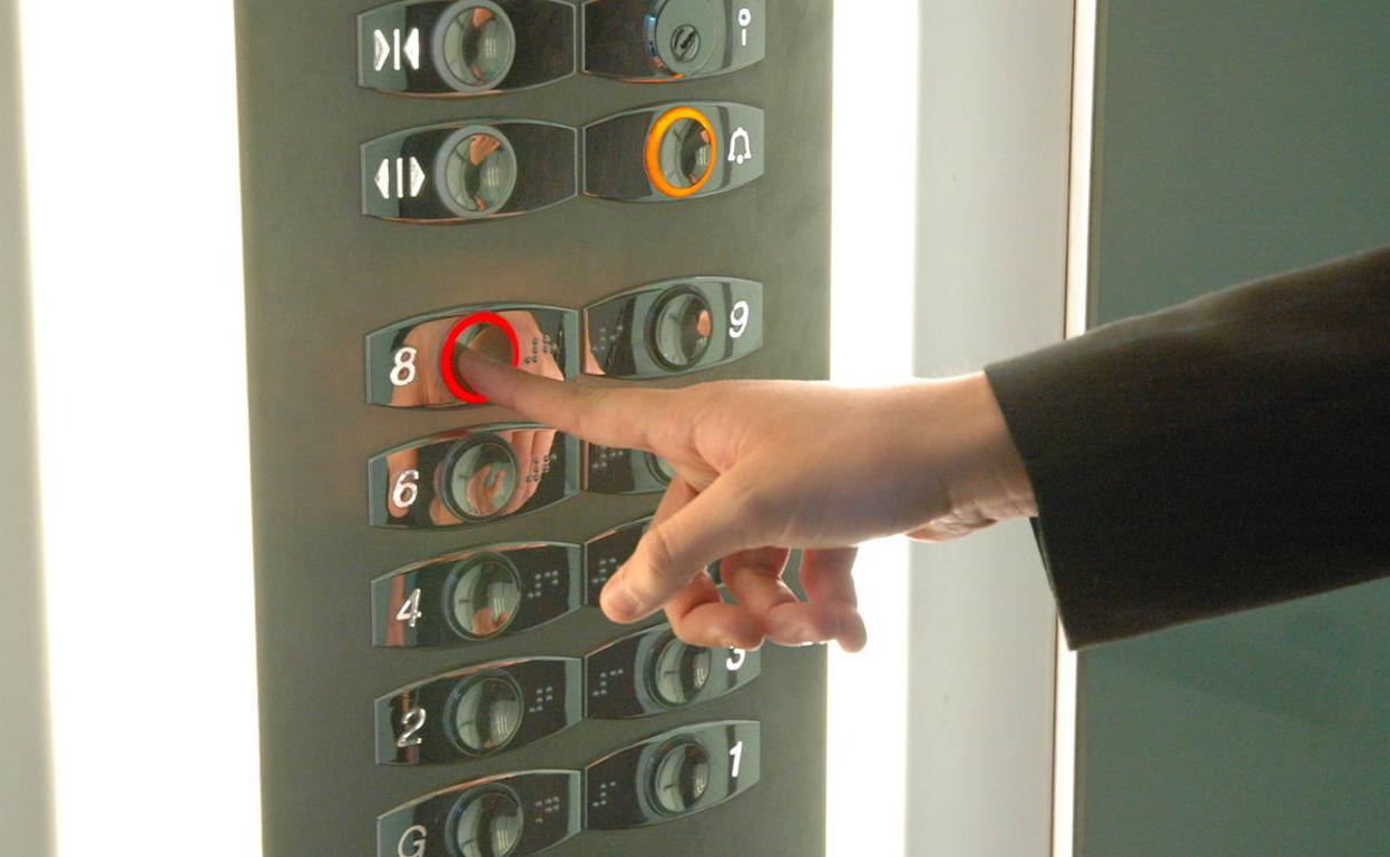 Vecina de una comunidad pulsa el botón del ascensor.