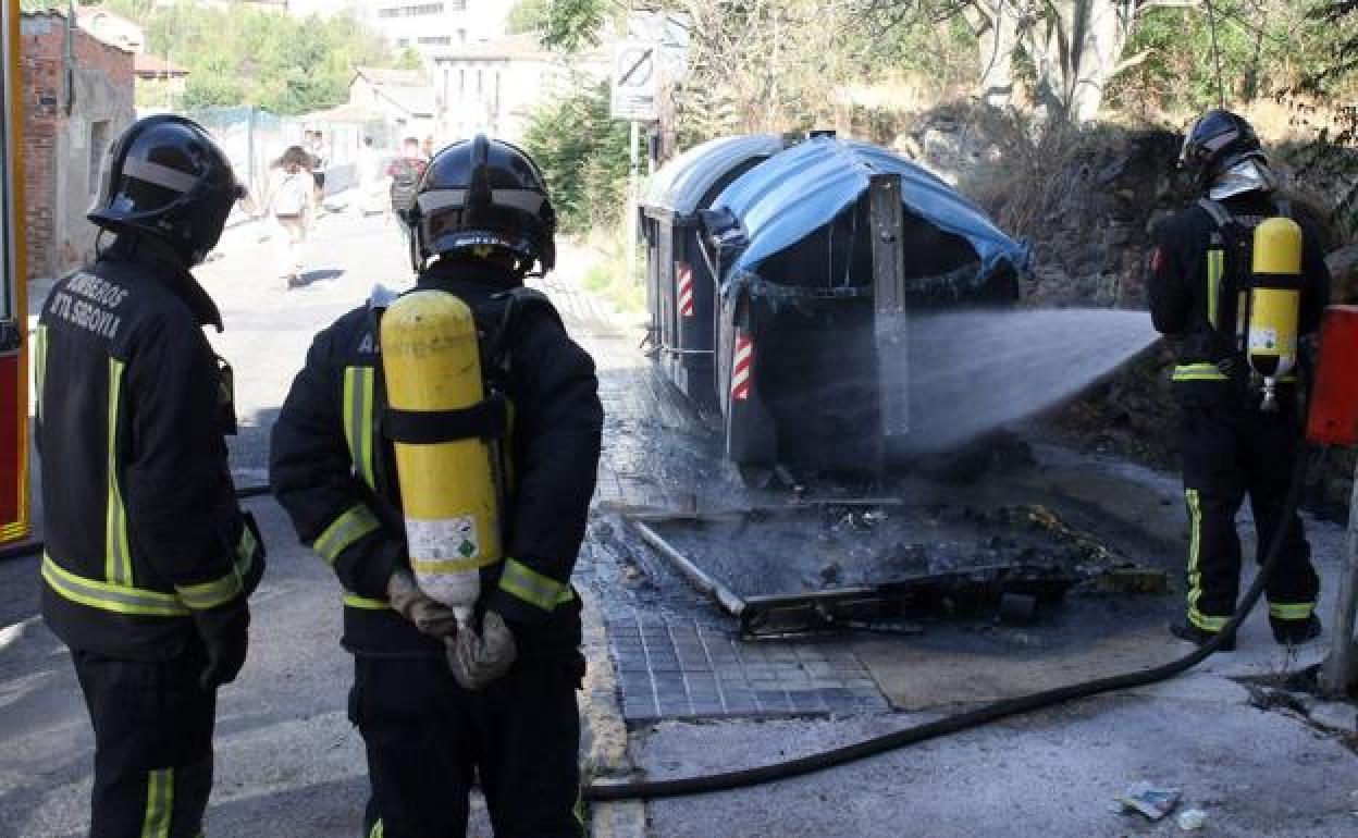 Bomberos apagan el fuego en varios contenedores en la calle Antonio Coronel, el pasado agosto. 