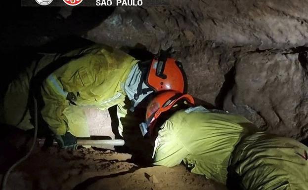 Dos bomberos tratan de rescatar a sus compañeros atrapados en una cueva en Brasil.