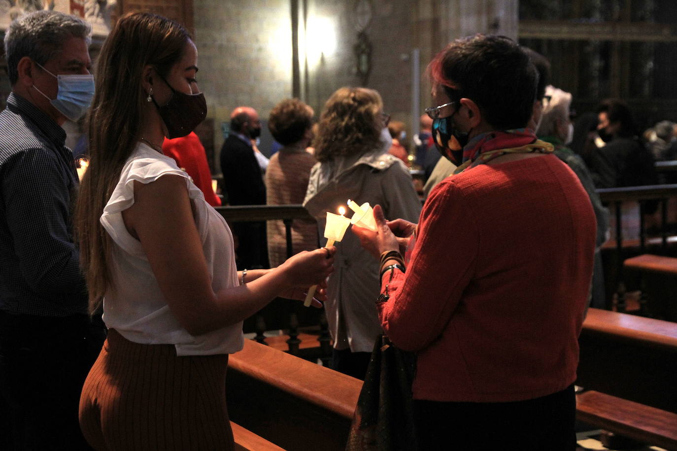 Asistentes a una eucaristía en Segovia durante la pandemia encienden unas velas. 