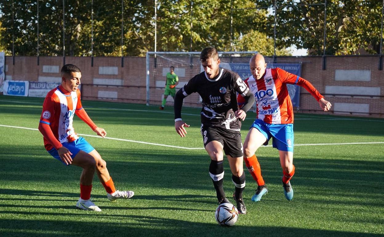 Jairo, rodeado de dos jugadores del Navalcarnero. 