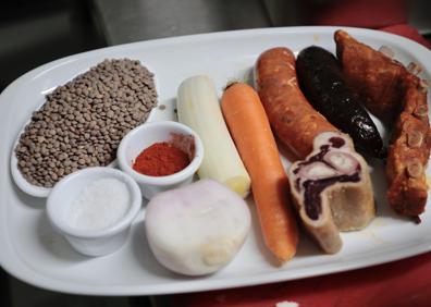 Imagen secundaria 1 - Lolo Astorga, chef de Los Ilustres, posa son sus lentejas que, como se ve abajo, llevan todos los sacramentos, además de verduras y pimentón.