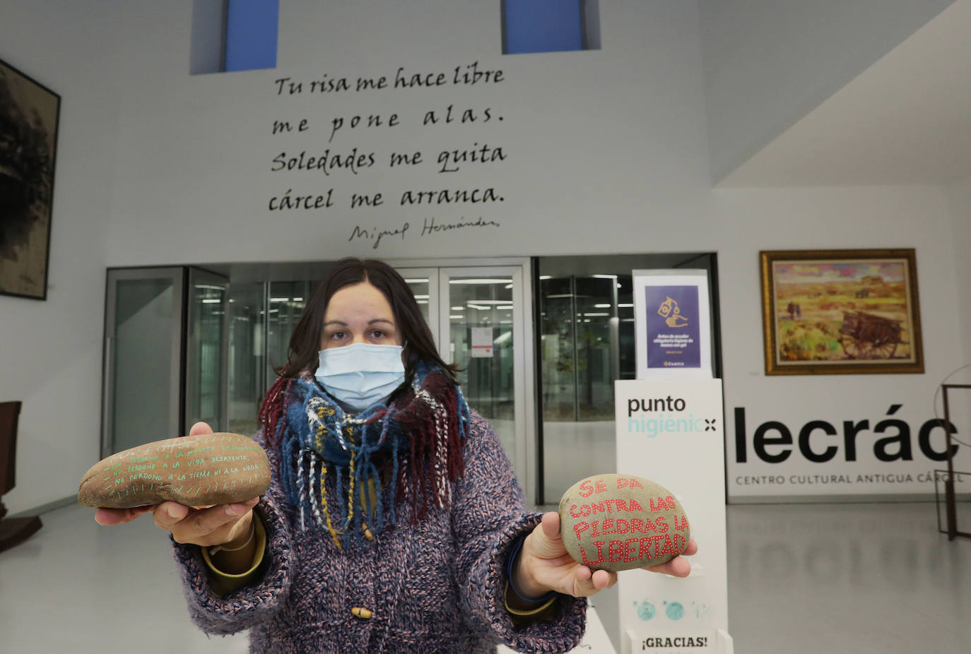 Irene Canales sujeta dos piedras en el centro Lecràc, cuya entrada está presidida por unos versos del poeta. 