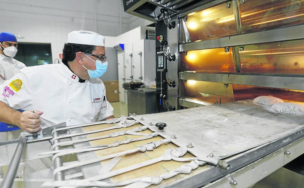 Carlos Mariel mete una bandeja de pan en el horno.