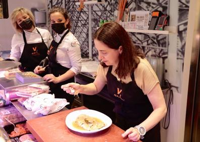 Imagen secundaria 1 - Arriba, Elena Arzak se asoma a las entrañas del lechazo mientras Javier de la Heras le explica las partes con las que se hace la asadurilla. Abajo, prueba las pechugas escabechadas, en presencia de Esther Rodríguez y su hija, Parquel Mayo, y observa el producto de algunos puestos. 