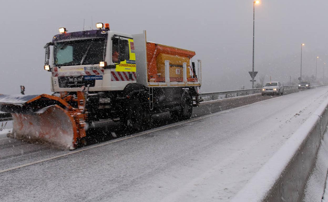 Una máquina quitanieves reitira la nieve acumulada en una carretera.