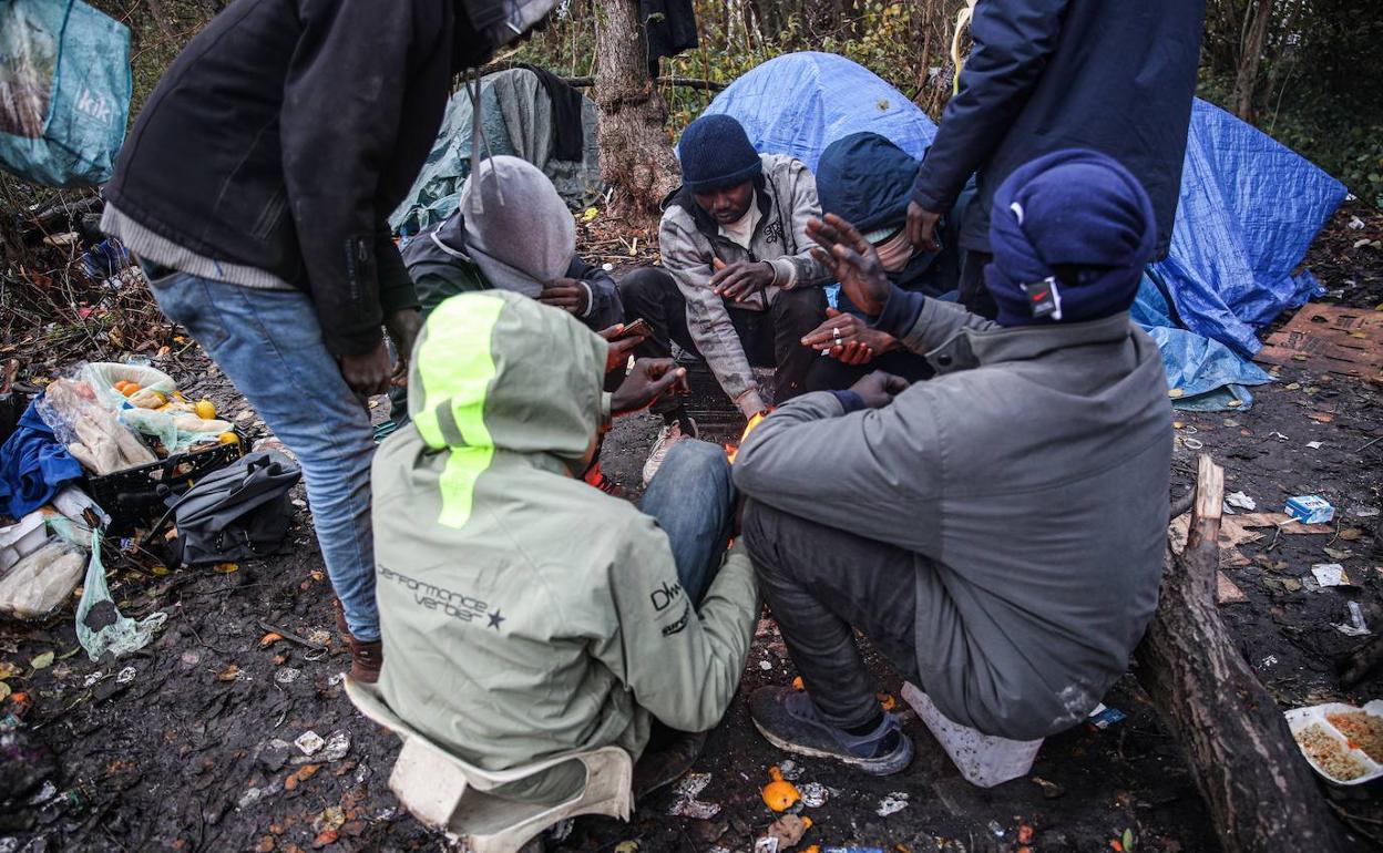 Un grupo de migrantes se calientan en una hoguera. 