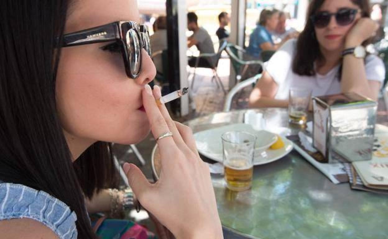 Una joven fuma en una terraza. 