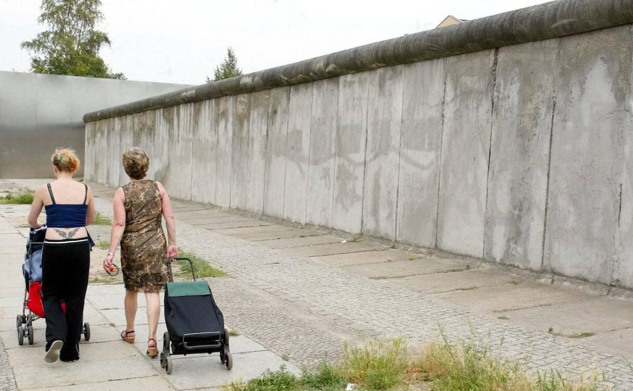 Dos mujeres pasean junto a un tramo del antiguo muro de Berlin. 