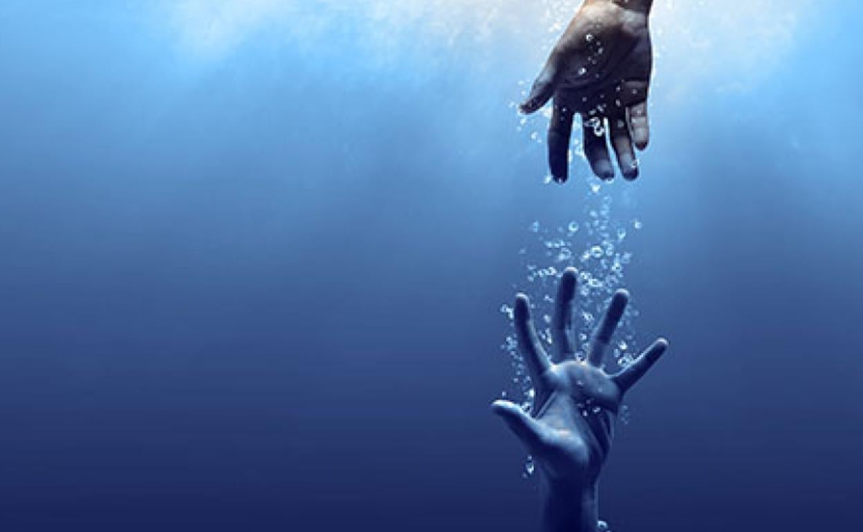 Dos manos intentan agarrarse bajo el agua. 