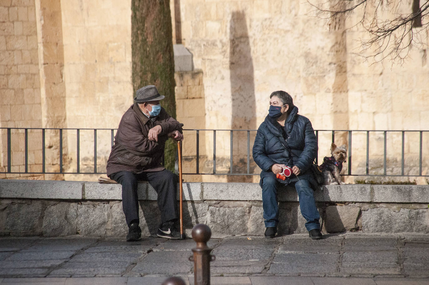 Dos personas hablan, junto a la iglesia de San Millán, con la mascarilla puesta.