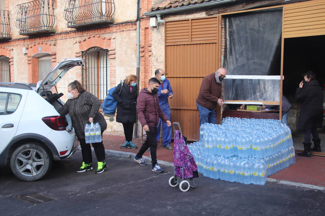 Vecinos recogen agua embotellada de Lastras de Cuéllar este lunes por la mañana.