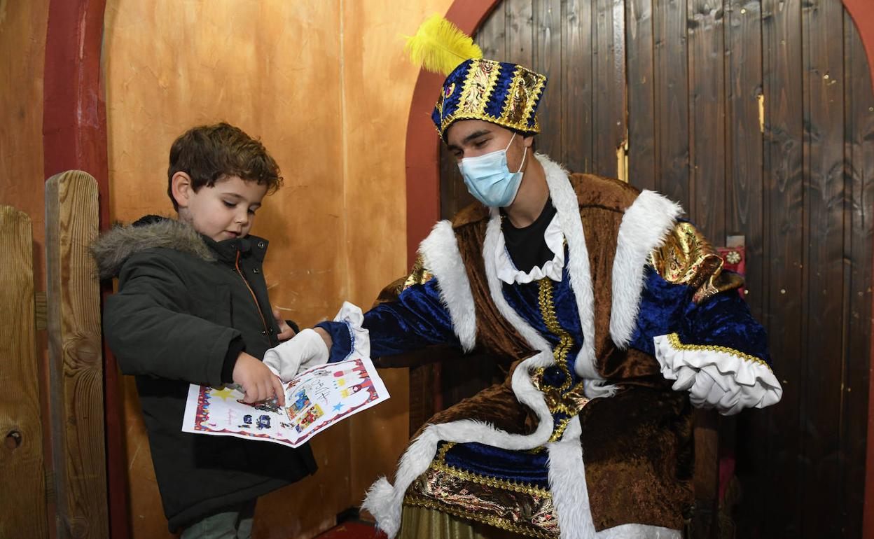 Un niño entrega su carta al Cartero Real, que está ubicado ante la fachada del Ayuntamiento de la capital.