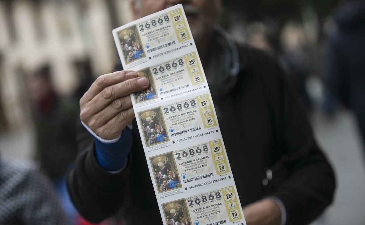Un hombre muestra una tira de boletos de la lotería del Niño. 