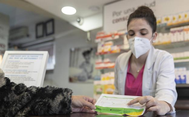 Una farmacéutica vende un test de antígenos.