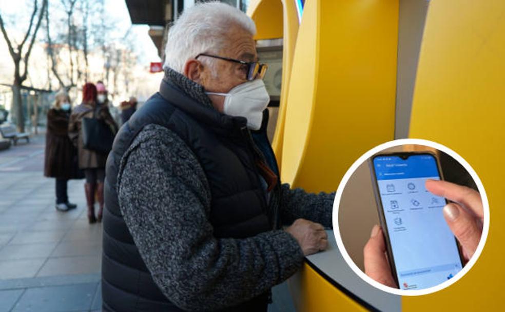 Antonio Colás realiza gestiones en el cajero de una sucursal bancaria del Paseo Zorrilla. En pequeño, una mujer utiliza la aplicación Sacyl Conecta. 