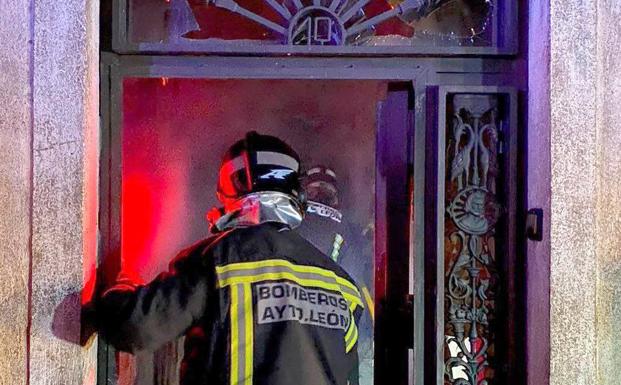 Varios bomberos acceden al interio de la vivienda incendiada.