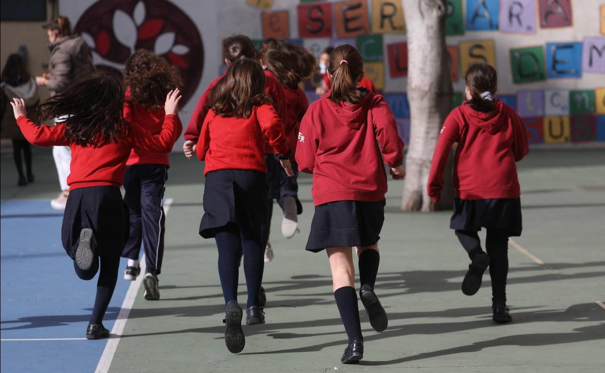 Un grupo de niñas corren en el patio del colegio. 