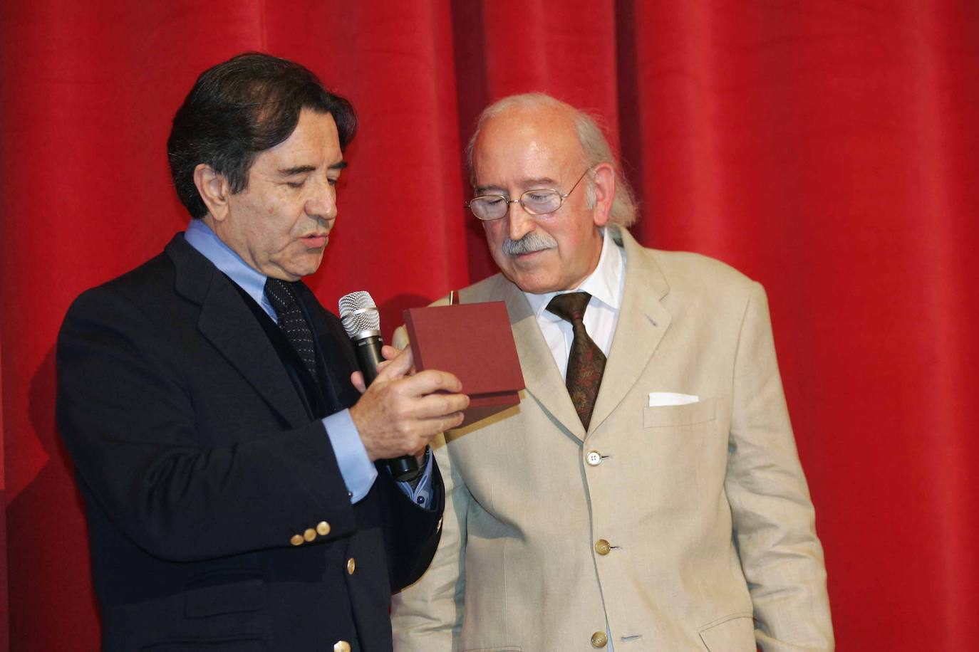 Enrique Cornejo muestra a Juan Antonio Quintana la placa con su nombre que se iba a colocar en la segunda butaca de la fila 1 durante el homenaje que el actor recibió en el Teatro Zorrilla de Valladolid en diciembre de 2009.