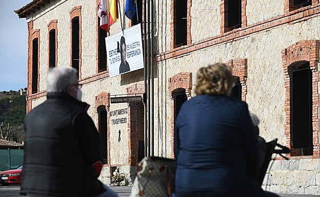 Dos vecinos de Traspinedo, sentados en los bancos de la plaza del Ayuntamiento. De fondo, el cartel que rememora a Esther López. 
