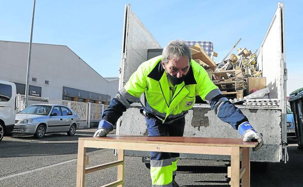 Un trabajador de la empresa de aseo urbano recoge una mesa en el Polígono. 