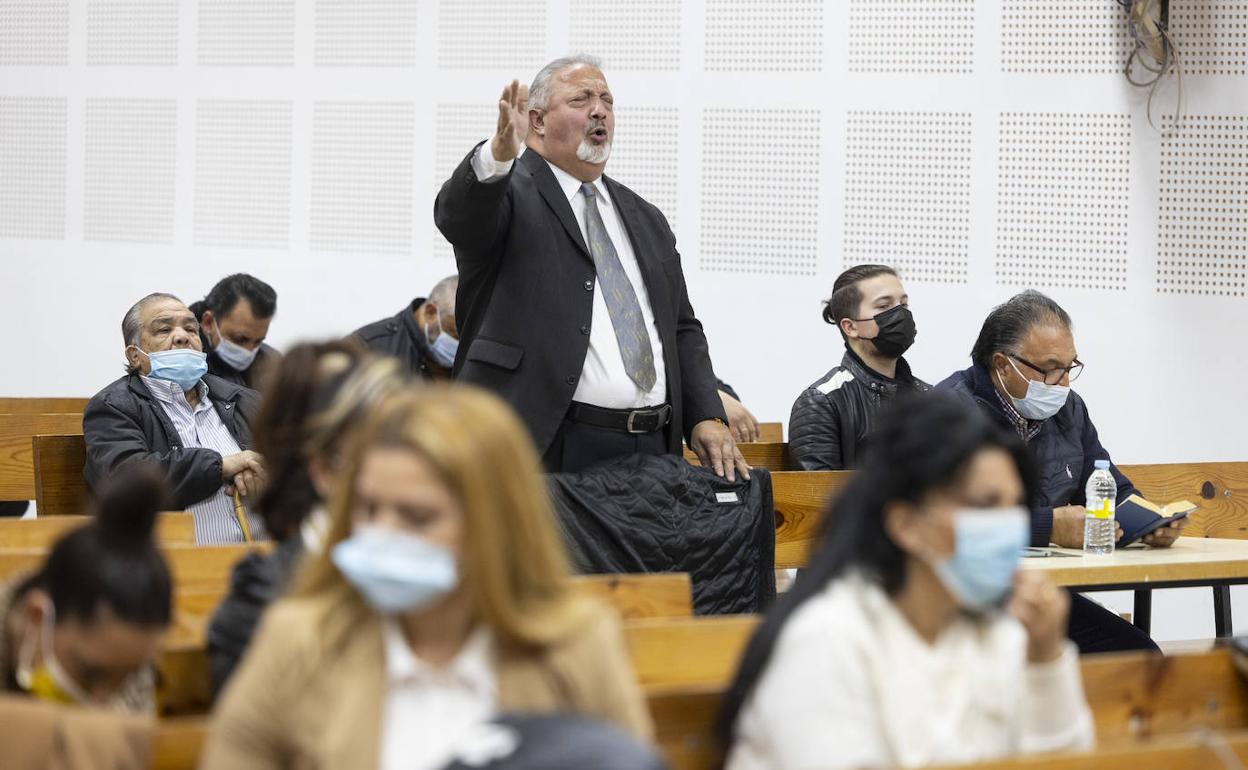 Un hombre se pone en pie para orar durante un culto evangelista Pentecostal en la iglesia.