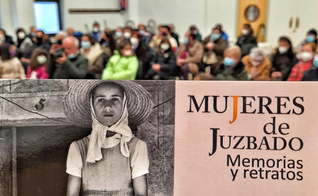 ortada del libro 'Mujeres de Juzbado. Memorias y retratos', en un salón de actos repleto de vecinos. 