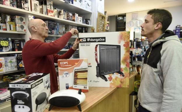 Un hombre compra un radiador eléctrico en un comercio.