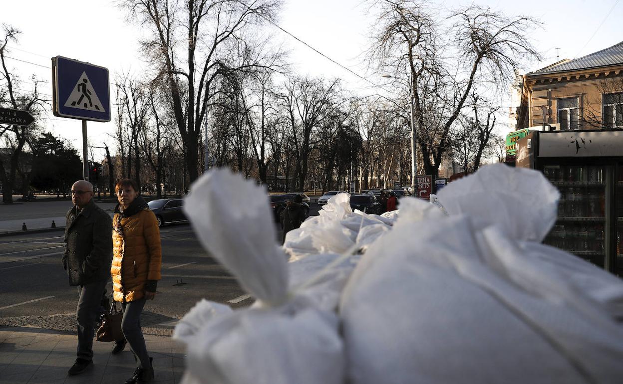 Dos personas pasan ante una barricada de sacos terreros en la plaza Soborna de Odesa.