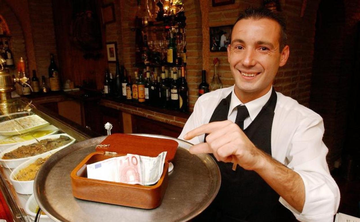 Un camarero muestra el bote de las propinas.