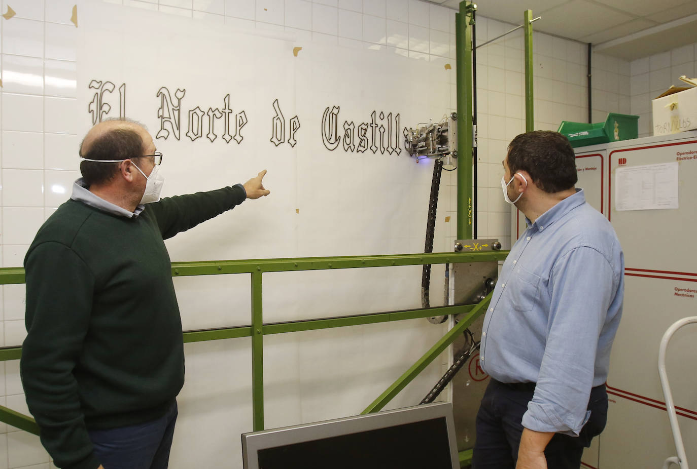 El tutor, Roberto González, junto al director del centro Camino de la Miranda, Ramón Polanco, señala el robot y la estampación que hace de la mancheta de El Norte de Castilla. 