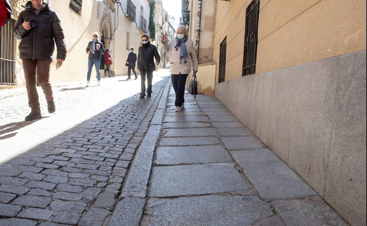 Transeúntes pasan por la acera y calzada de la calle Daoiz. 