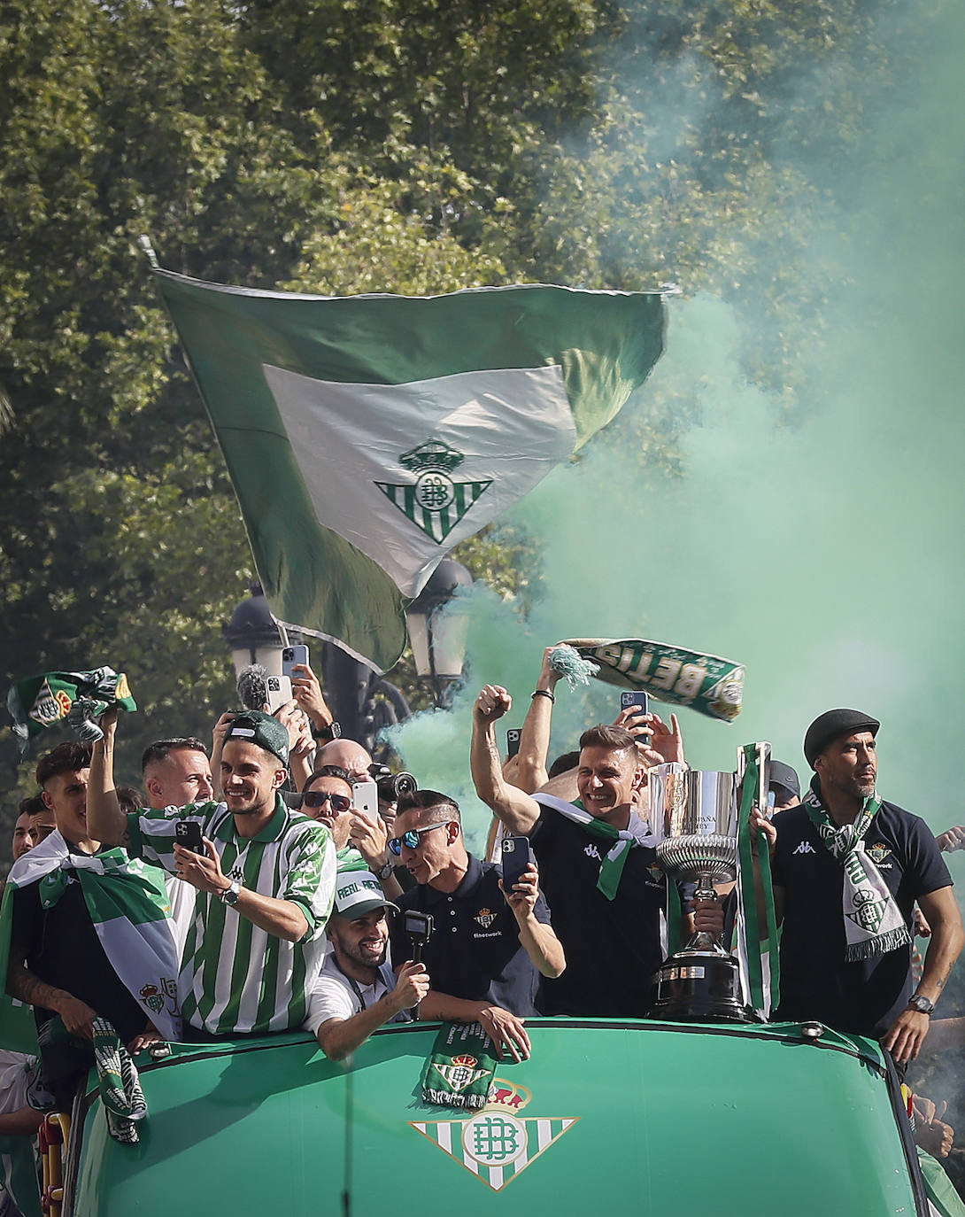 Jugadores del Betis saludan desde el autocar durante su recorrido con destino al ayuntamiento de Sevilla, para celebrar su título de Copa del Rey.