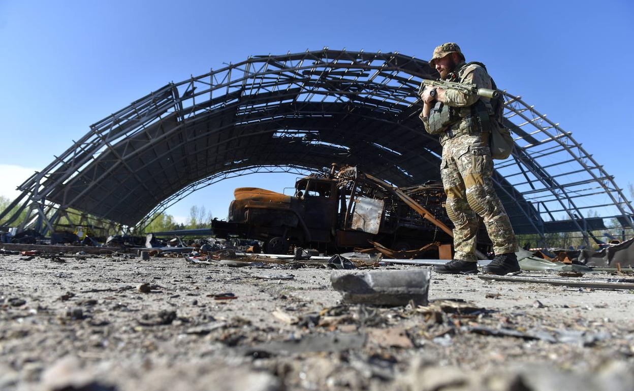 Un militar de Ucrania cerca de un hangar dañado que contiene los restos del avión de transporte ucraniano.