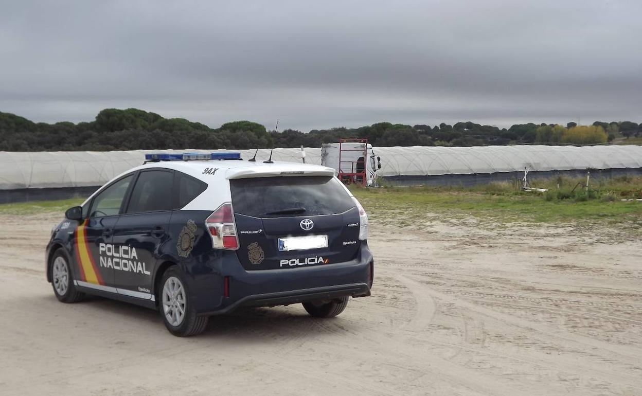 Un vehículo de la Policía Nacional junto a una nave agrícola. 