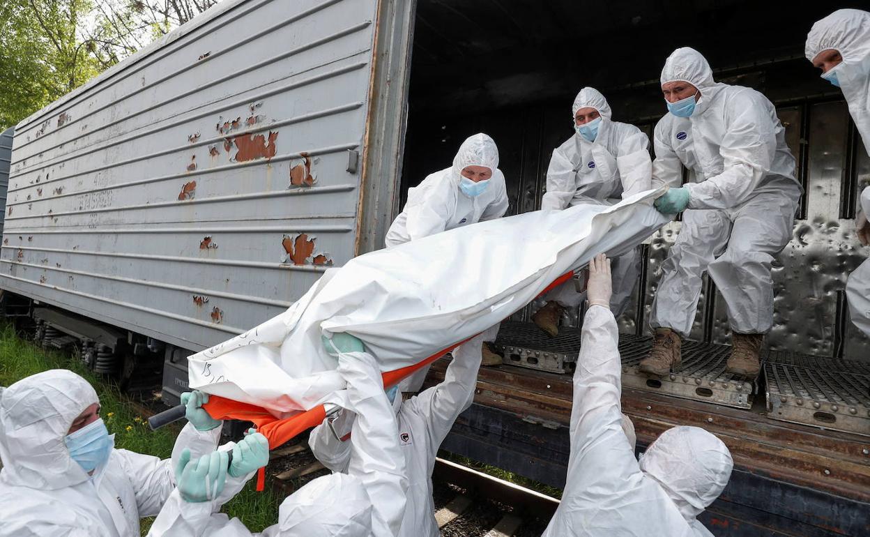 Militares ucranianos cargan cuerpos de soldados rusos en Kiev. 