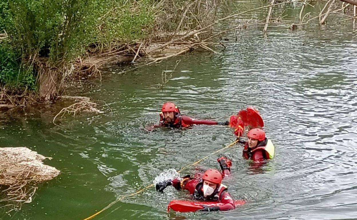 Los bomberos, durante las labores de rescate del cuerpo. 