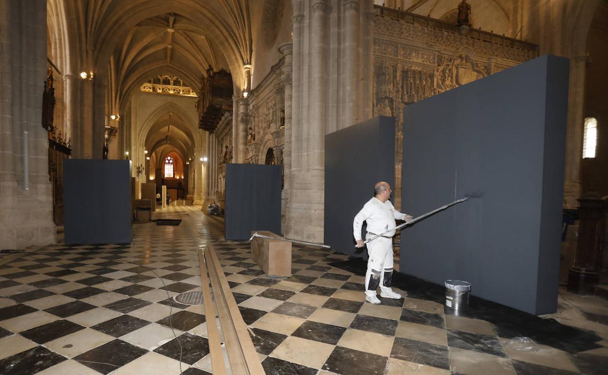 Un trabajador pinta uno de los paneles instalados en los laterales de la Catedral de Palencia.