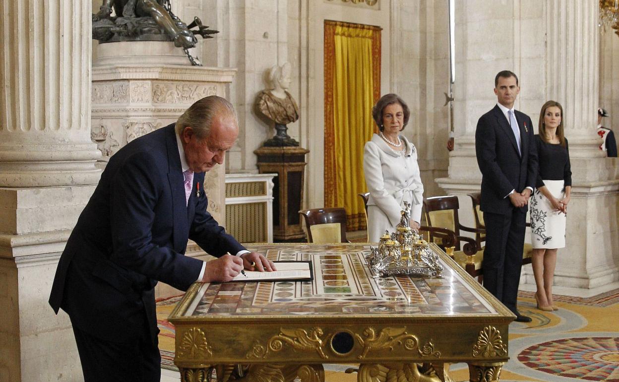 El Rey Juan Carlos I sanciona la ley orgánica por la que se hace efectiva su abdicación del trono español, en presencia de la Reina Sofía y los Príncipes de Asturias, en una ceremonia celebrada en el Salón de Columnas del Palacio Real, el 18 de junio de 2014. 