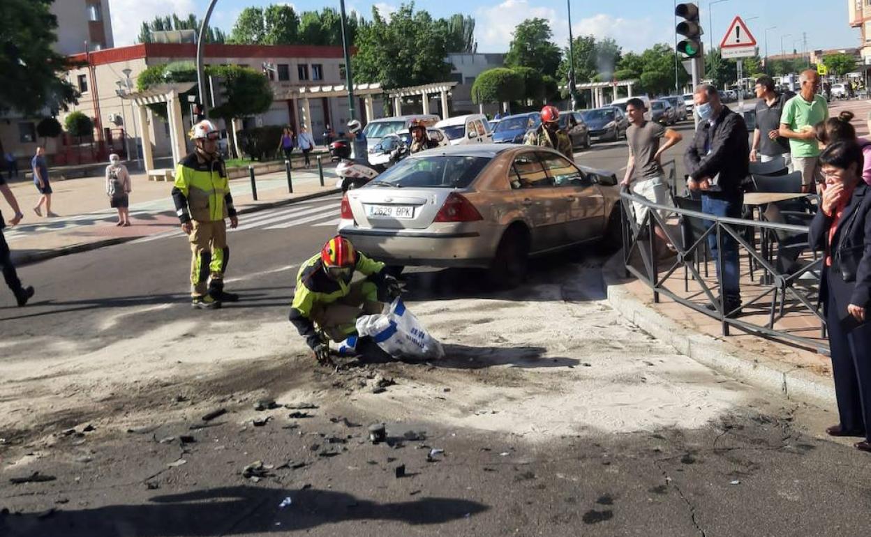 Dos bomberos limpian el cruce donde se produjo el choque entre dos vehículos. 