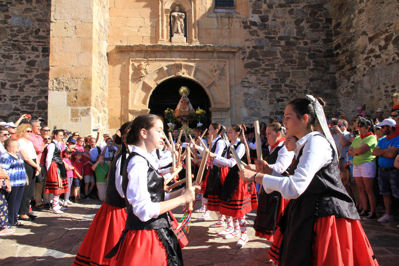 Los grupos de paloteo preceden el paso de la Virgen del Castillo por uno de los arcos de flores de papel en Bernardos. 