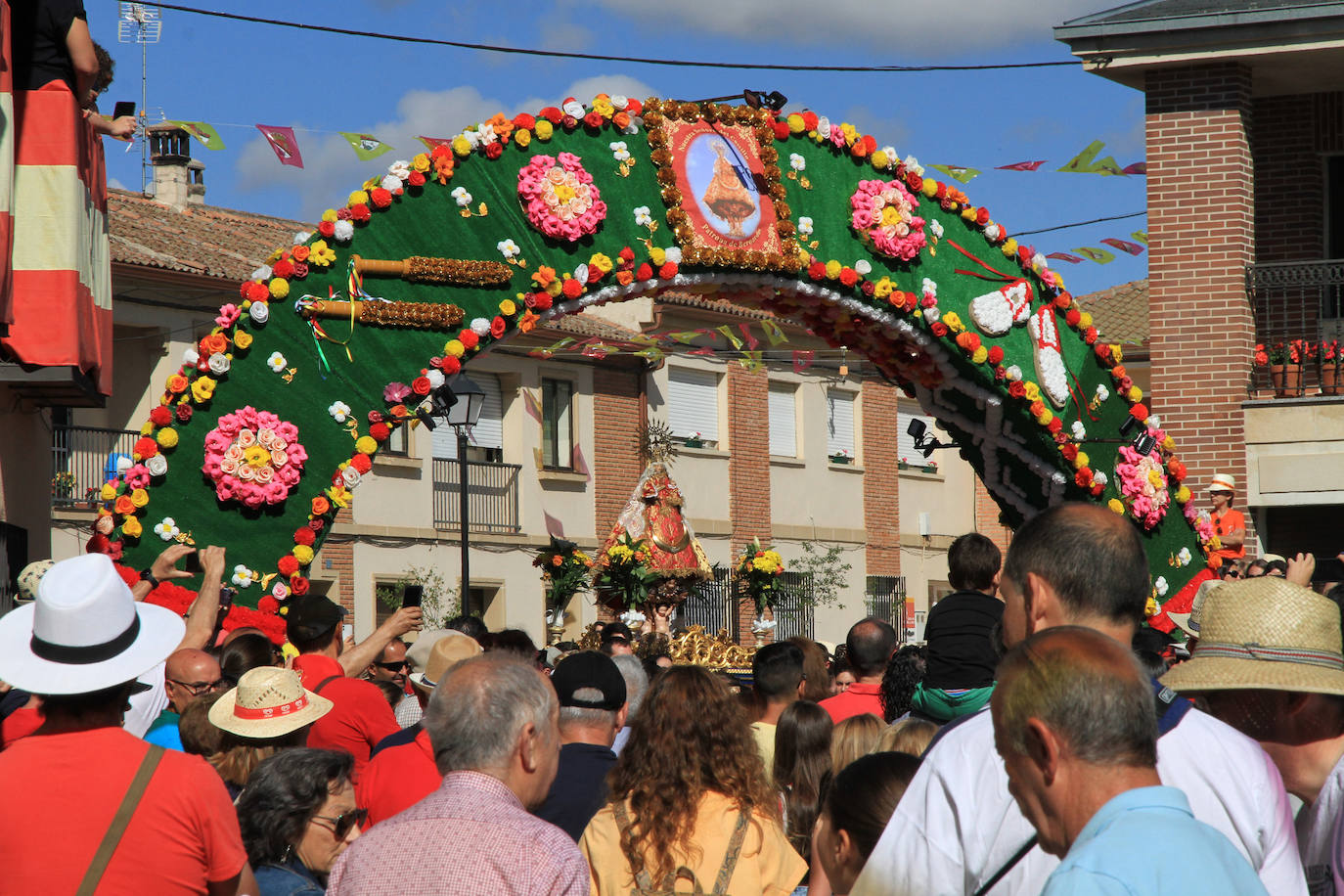 Los grupos de paloteo preceden el paso de la Virgen del Castillo por uno de los arcos de flores de papel en Bernardos. 