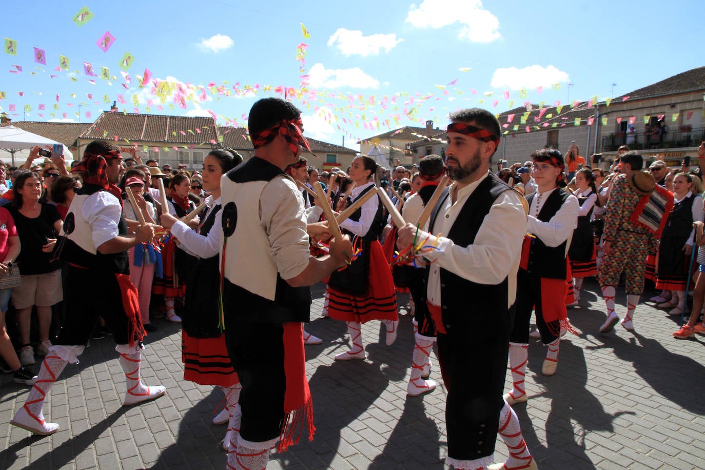 Los grupos de paloteo preceden el paso de la Virgen del Castillo por uno de los arcos de flores de papel en Bernardos. 