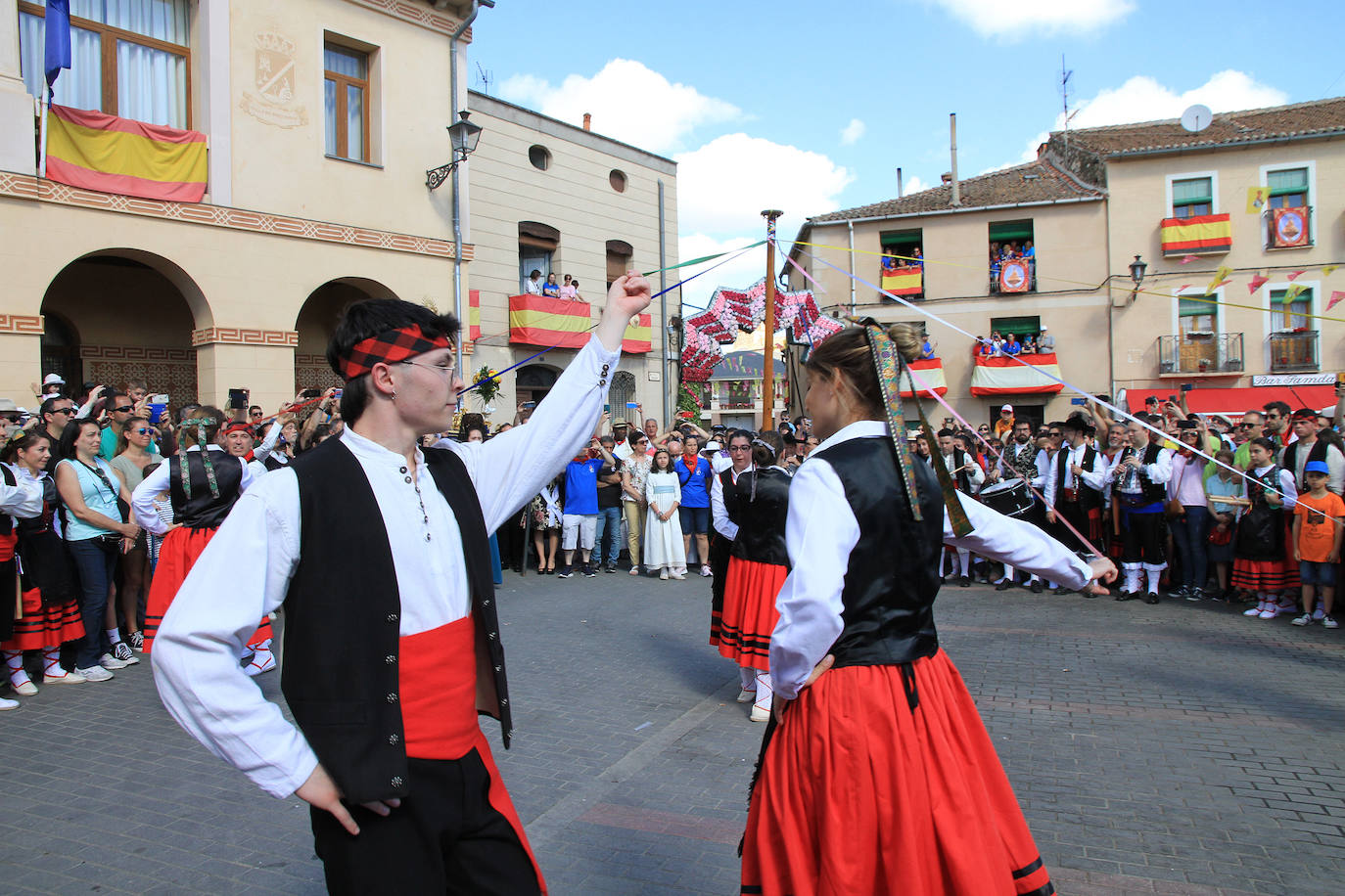 Los grupos de paloteo preceden el paso de la Virgen del Castillo por uno de los arcos de flores de papel en Bernardos. 