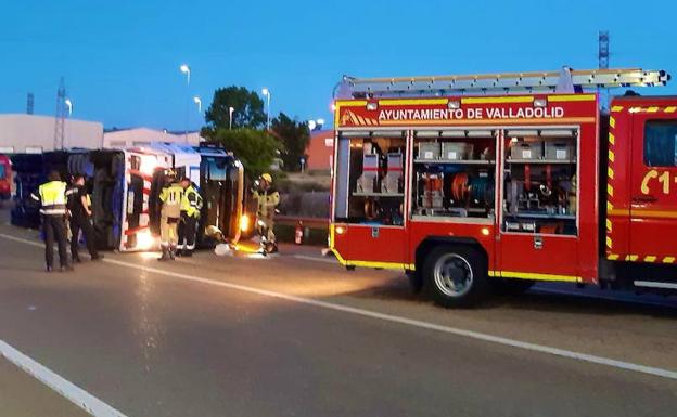 Efectivos de los bomberos junto al vehículo pesado que ha quedado volcado sobre la calzada. 