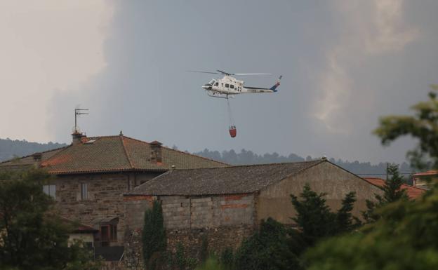 Un helicóptero sobrevuela Villardeciervos, con el humo amenazante al fondo. 