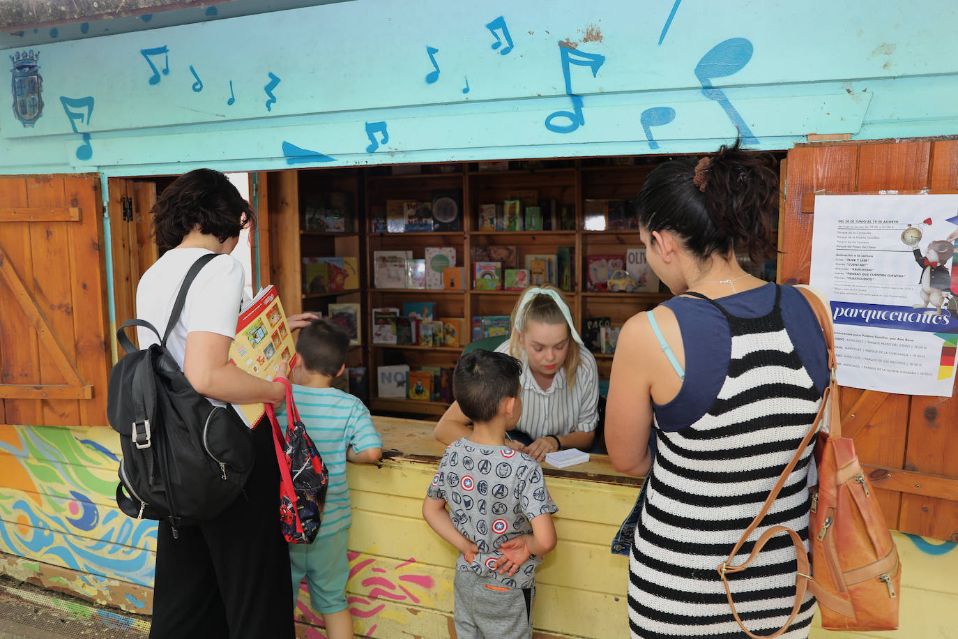 La encargada de la biblioteca de la Huerta de Guadián atiende a dos niños. 