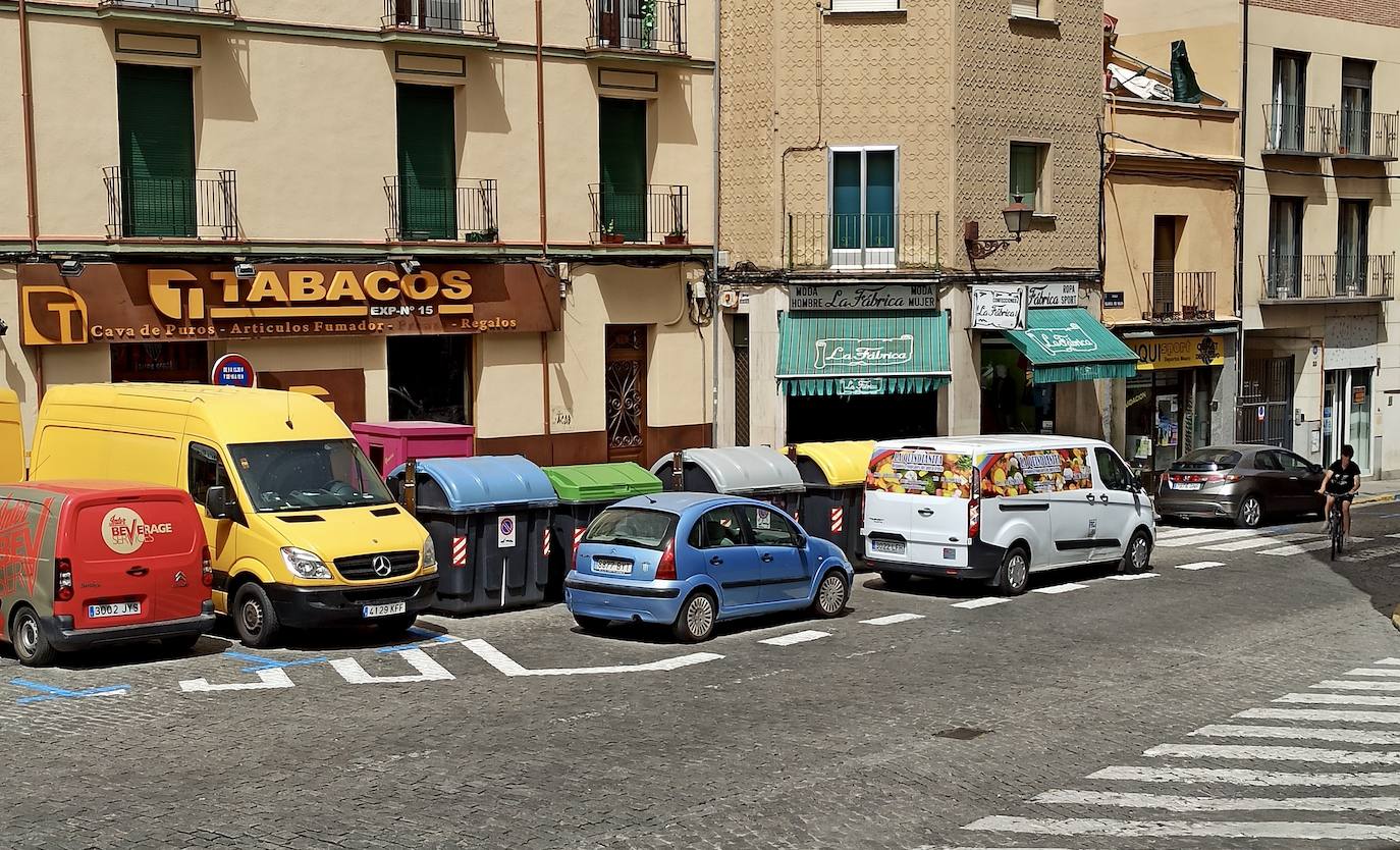 Dos vehículos en doble fila sobre el carril bici obligan a un ciclista a circular por el medio de la calle.